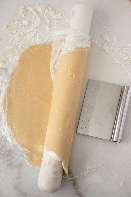 perfect pie crust, Keep the plastic on top of the pie circle and roll around the rolling pin with the help of the bench scrapper to lift and transfer to pie dish