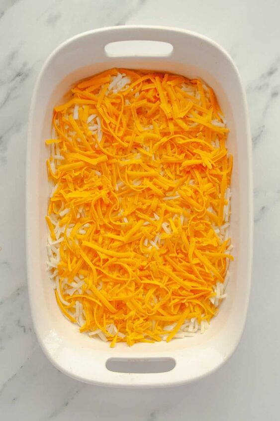 easy cheesy hashbrown casserole without soup, Half of hashbrowns salt cheddar cheese in a baking dish