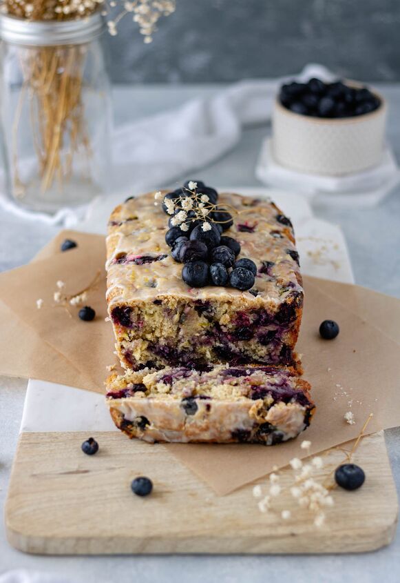 Lemon Blueberry Zucchini Bread sitting on a marble cutting board with a slice cut from it