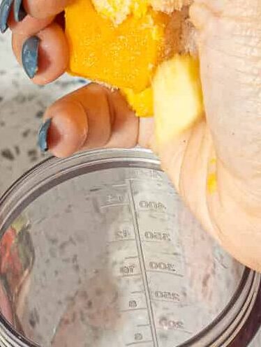 how to make fruit leather in a food dehydrator, person adding frozen mango chunks to small blender