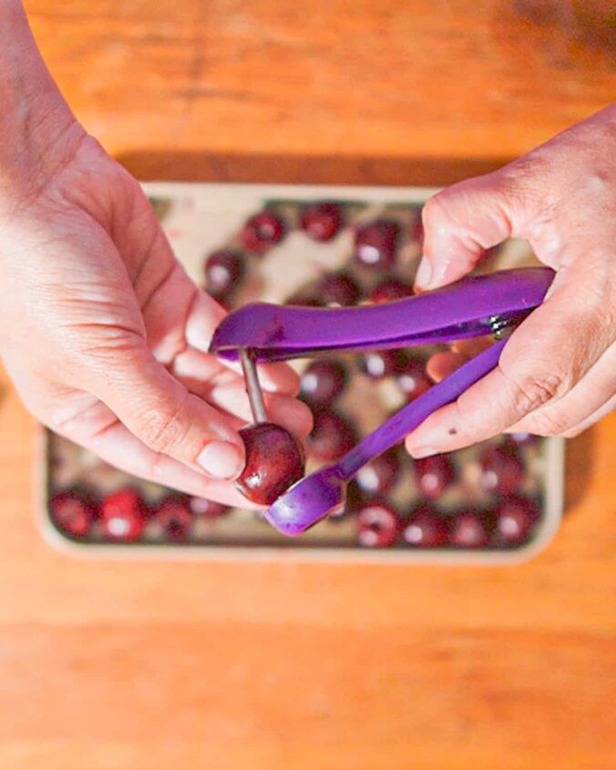how to dehydrate cherries, person holding purple cherry pitter