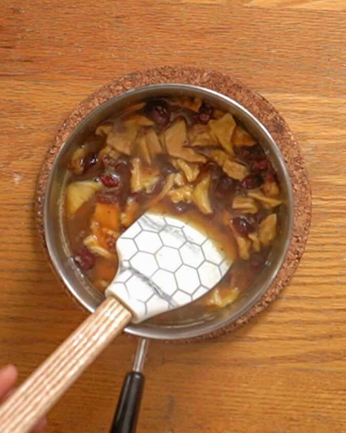 dried cranberry sauce with pineapple, person stirring dried fruit cranberry sauce in a small saucepan with a spatula