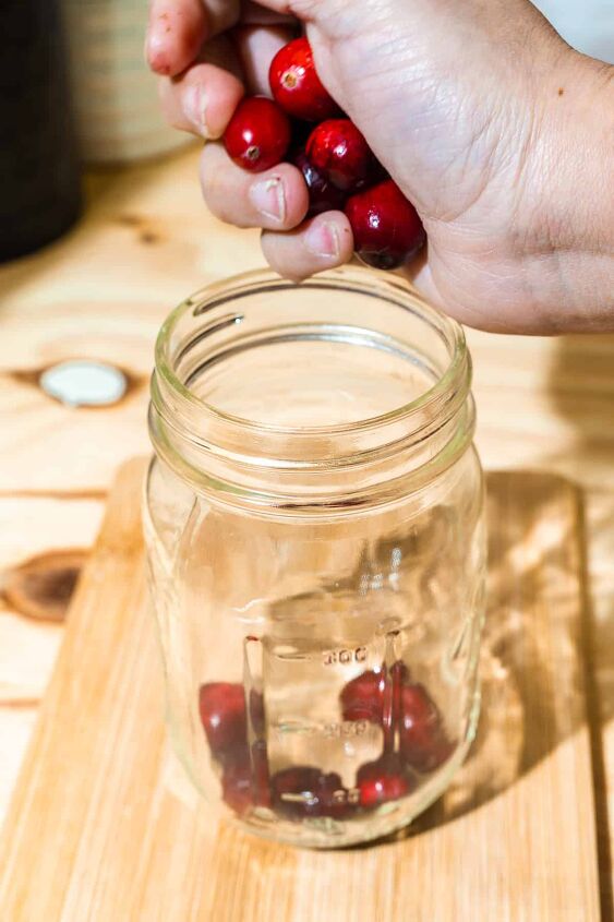 honey fermented cranberries, person placing cranberries in mason jar