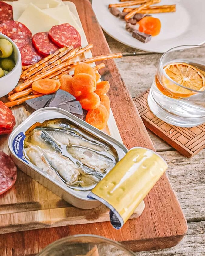 easy small charcuterie board for two, small charcuterie board with pepperoni cheese sardines olives and a cocktail with orange slice