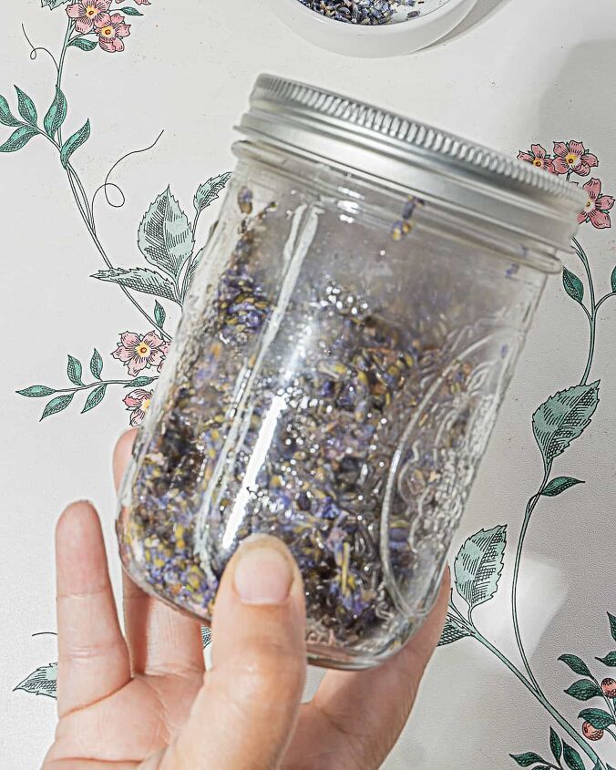 honey lavender lemonade, person holding mason jar with water and dried lavender buds that are infusing