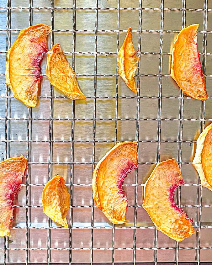 how to dry peaches in a dehydrator, dehydrated peaches on a metal rack on a silver background
