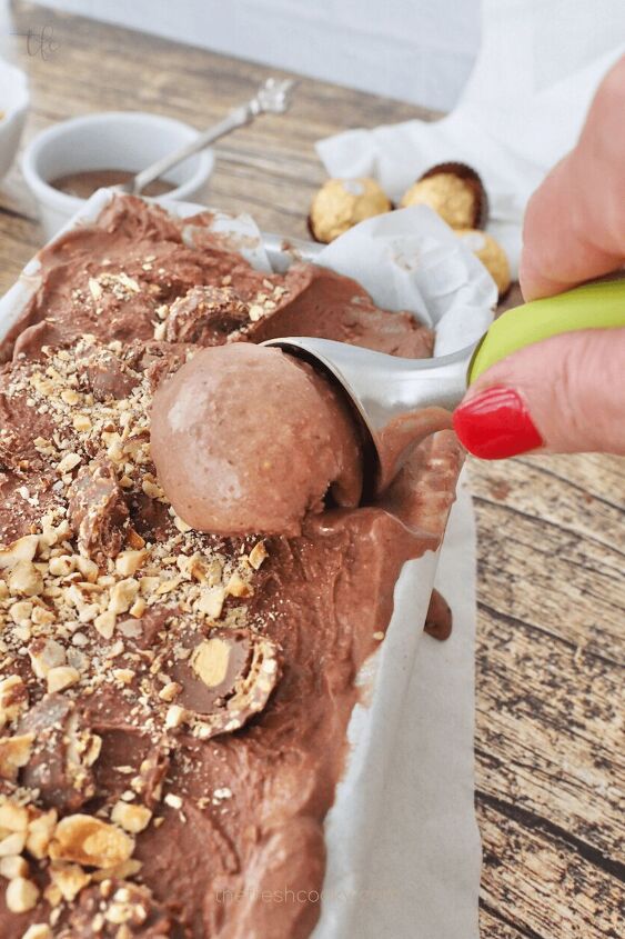 Ferrero Rocher Ice Cream in pan with hand using ice cream scoop and scooping a big scoop to put into a bowl