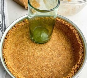no bake cheesecake with cool whip, graham cracker crumbs pressed into a springform pan with a green glass