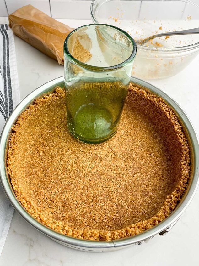 no bake cheesecake with cool whip, graham cracker crumbs pressed into a springform pan with a green glass
