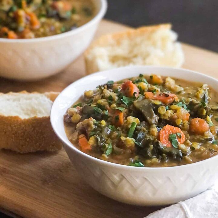 vegetarian lentil farro stew, Vegetarian Stew in a white bowl with crusty bread on a wood cutting board