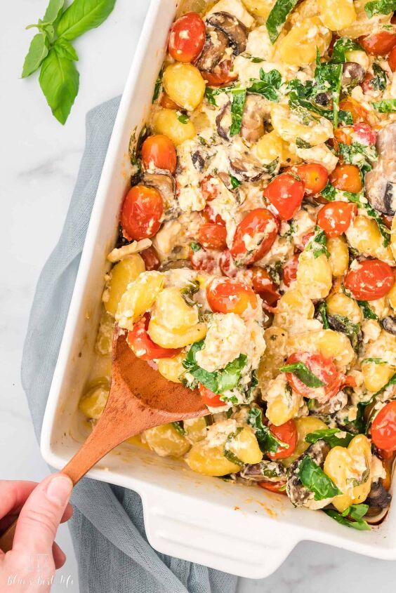 baked feta cheese with gnocchi and tomatoes, A baking dish with tomatoes mushrooms spinach and gnocchi with a creamy sauce