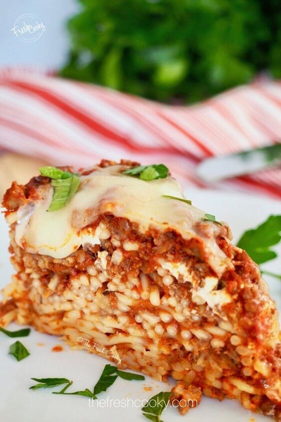 easy baked spaghetti pie, Slice of baked spaghetti pie on a white plate with bits of parsley on top