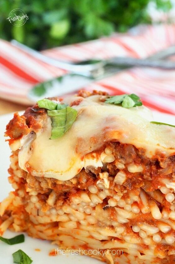 easy baked spaghetti pie, Close up of melty cheese baked spaghetti pie on white plate with meat sauce