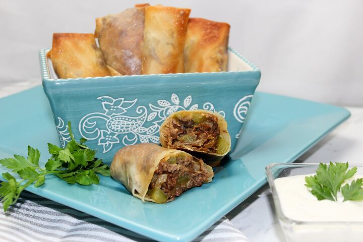 the best philly cheesesteak eggrolls recipe, philly cheesesteak eggroll on a blue plate