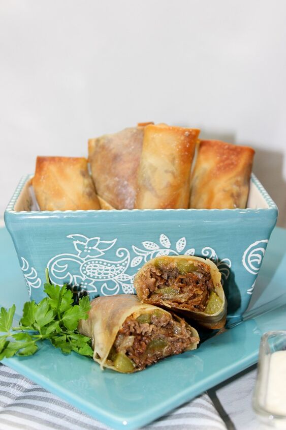 the best philly cheesesteak eggrolls recipe, philly cheesesteak eggroll on a blue plate