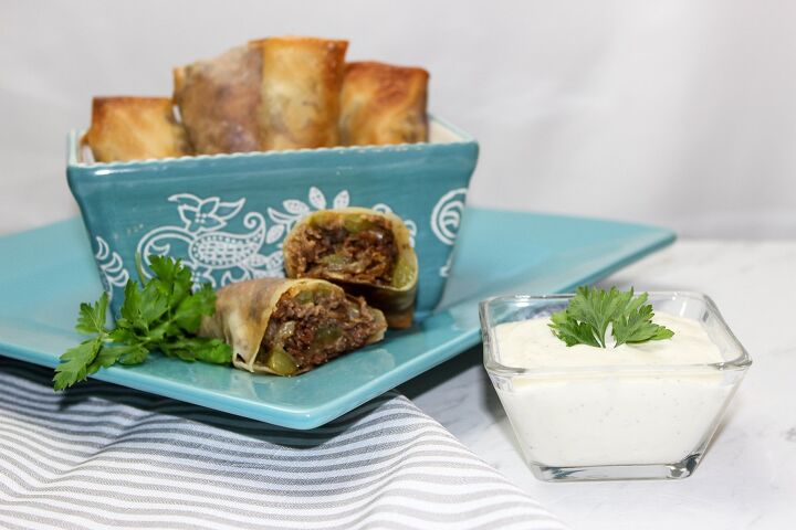 the best philly cheesesteak eggrolls recipe, philly cheesesteak eggroll on a blue plate