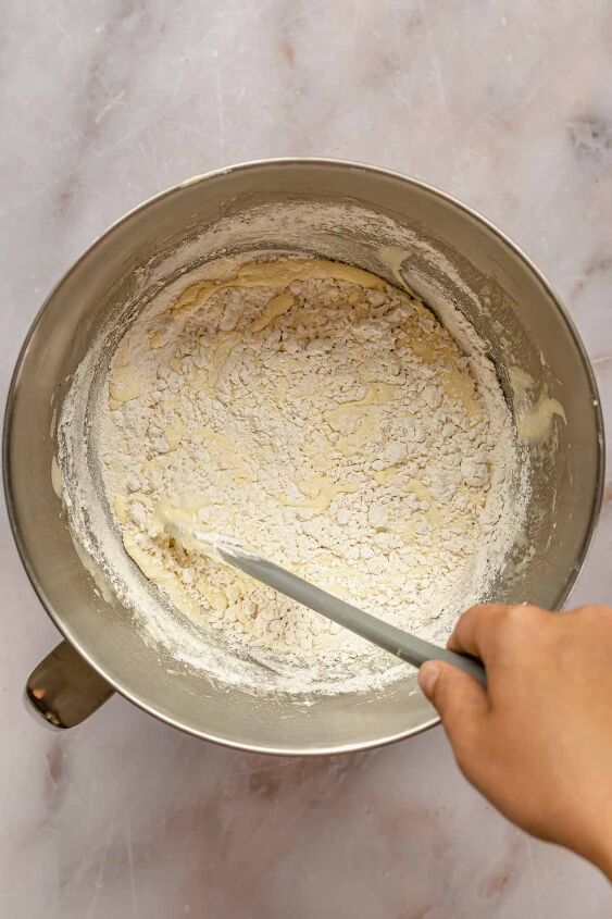 caramel tres leches cake, A hand and spatula folds flour into cake batter