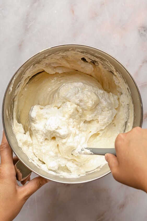 caramel tres leches cake, A hand folds whipped egg whites into cake batter