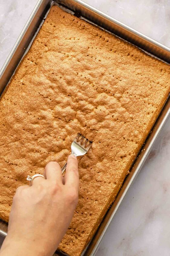 caramel tres leches cake, A fork pricks holes into the baked sponge cake all over