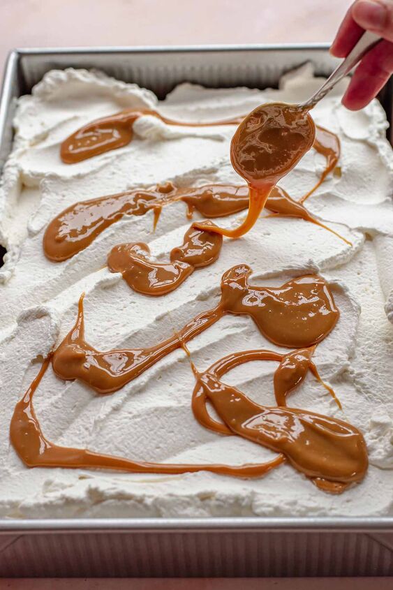 caramel tres leches cake, A spoon drizzles dulce de leche on top of the whipped cream