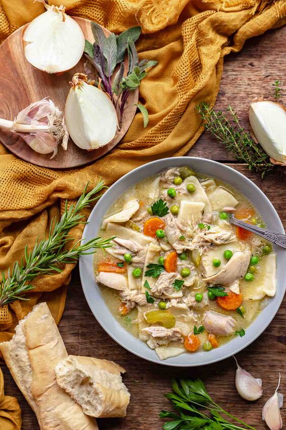 pennsylvania dutch chicken pot pie, Bowl of dutch chicken pot pie with onions bread and herbs surrounding the bowl