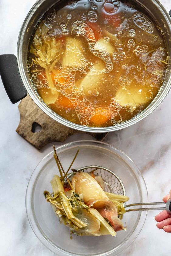 pennsylvania dutch chicken pot pie, A hand uses a spider to remove cooked vegetables from chicken stock