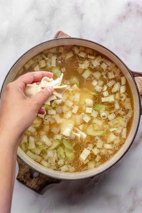 pennsylvania dutch chicken pot pie, A hand drops raw noodles into a pot of pot pie