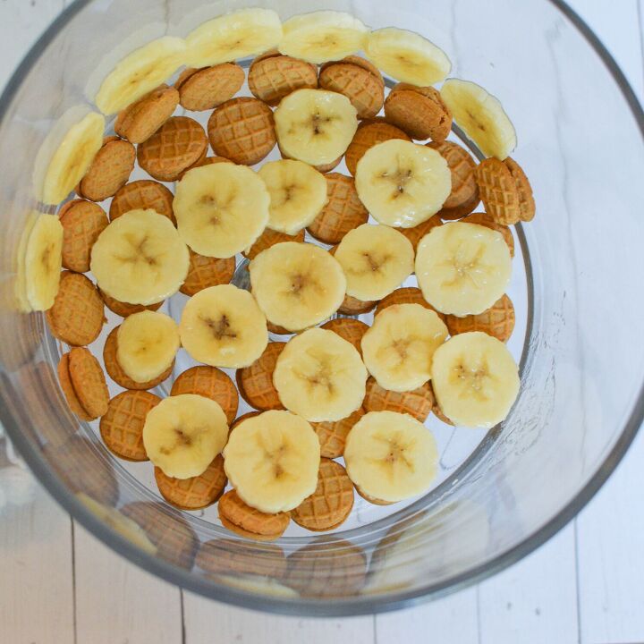 nutter butter no bake banana pudding, first step of laying bananas and cookies in trifle dish