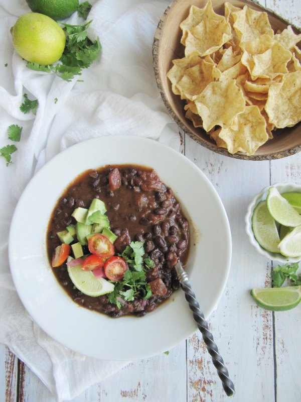 easy slow cooker black bean soup, easy black bean soup one white bowl and wood bowl of scoops chips