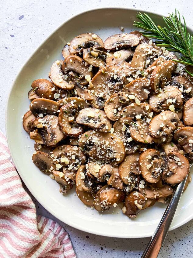 garlic butter mushrooms with rosemary, A plate of garlic butter mushrooms with a sprig of rosemary
