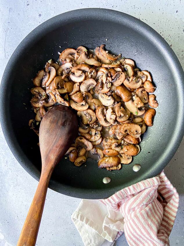 garlic butter mushrooms with rosemary, A pan of cooked mushrooms with a wooden spoon