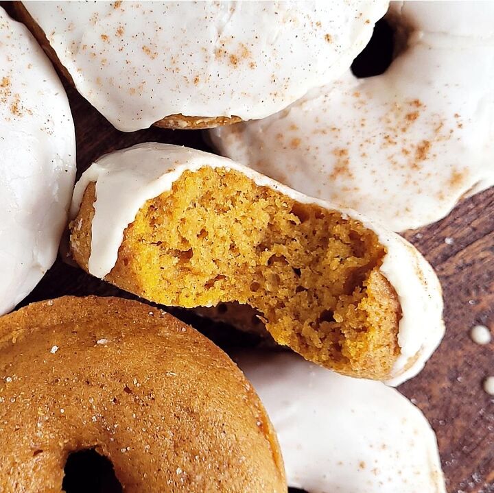 pumpkin donuts, functional image pumpkin donuts top down zoomed in on a donut with a bite missing to see the orange crumb