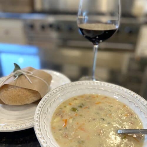how to make creamy and delicious baked potato soup recipe, white bowl clam chowder fresh roll fresh herbs glass of red wine bread plate