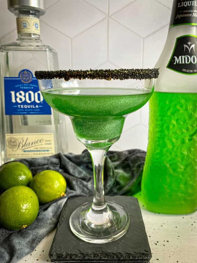 halloween margarita witches brew cocktail happy honey kitchen, Green margarita with a black sugar rim A bottle of midori melon liqueur and tequila are in the background with three limes