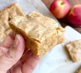 maple glazed apple blondies, Hand holding a maple glazed apple blondie with apples and other bars in the background