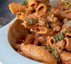 italian sausage pasta, a serving spoon holding up a serving of pasta covered in sausage red sauce