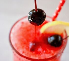 easy cranberry spritzer by the glass or pitcher, Top down image of glass of cranberry spritzer with a cherry dripping with juice being placed inside the bright red drink