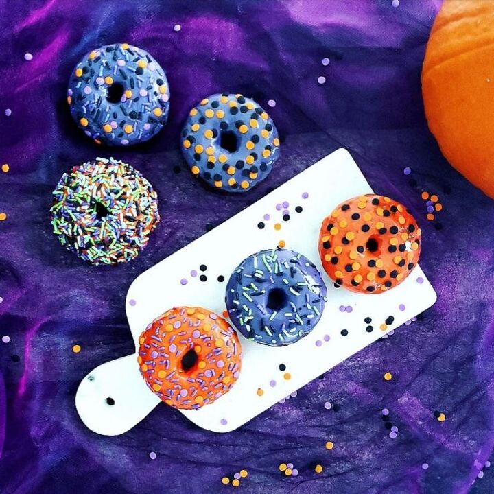chocolate halloween cookies, functional image halloween donuts with sprinkles top down view on purple tulle background baked halloween donuts with orange and purple icing and festive sprinkles