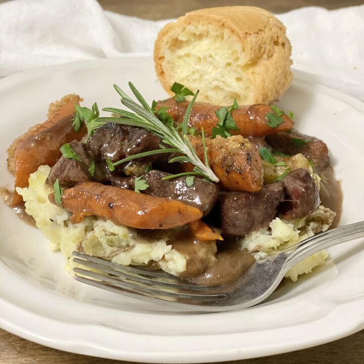 no peek oven beef stew, No Peek Oven Beef Stew over mashed potatoes in a white bowl with bread on the side
