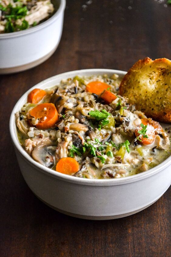creamy chicken and wild rice soup with parmesan herb toast, A bowl of creamy chicken with wild rice soup and a slice of parmesan herb toast another bowl sits behind and a pumpkin soup tureen