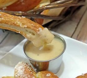 close up of homemade German pretzel being dunked in beer cheese dip