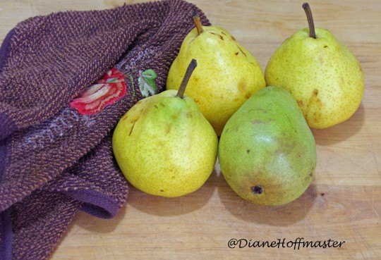 caramel vanilla pear sauce recipe, fresh pears on a wood cutting board with a kitchen towel