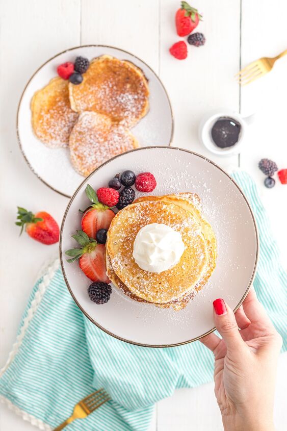 sweet cream pancakes, Hand holding plate of pancakes with berries