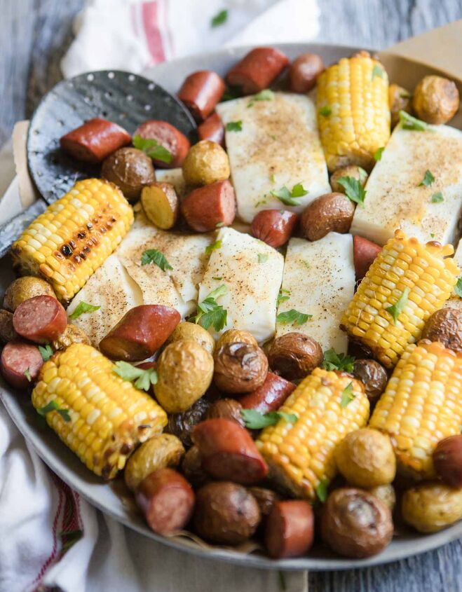 sausage sheet pan dinner, sausage sheet pan with halibut corn and potatoes on a round platter with seasoning on top