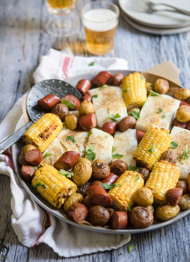 sausage sheet pan dinner, sausage sheet pan dinner with pieces of halibut corn and potatoes set against a gray backdrop