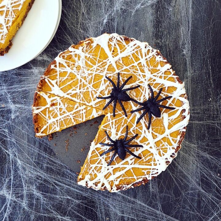 marshmallow spiderweb pumpkin tart, functional image marshmallow spiderweb pumpkin tart halloween dessert top down on a black surface one slice is cut from the tart and there are 3 black spiders on top