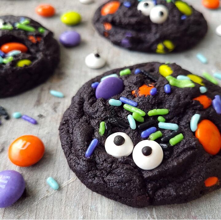 marshmallow spiderweb pumpkin tart, functional image dutch chocolate halloween cookies black cookies decorated with candy eyeballs halloween sprinkles and halloween m m s on a distressed gray surface