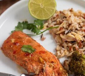 asian air fryer salmon, A round white dinner plate topped with a piece of salmon The salmon has a fork taking a piece from it There s wild rice and broccoli next to the salmon on the plate with a half of a lime and cilantro