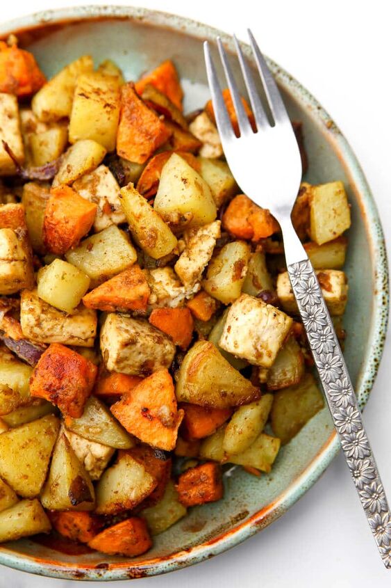 roasted root vegetables with tofu, A top view of a plate full of roasted root vegetables on a plate with a fork on the side