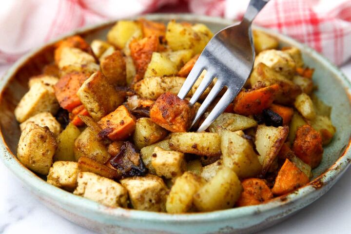 roasted root vegetables with tofu, A close up of a plate full of roasted veggies and tofu on a plate with a fork sticking in it